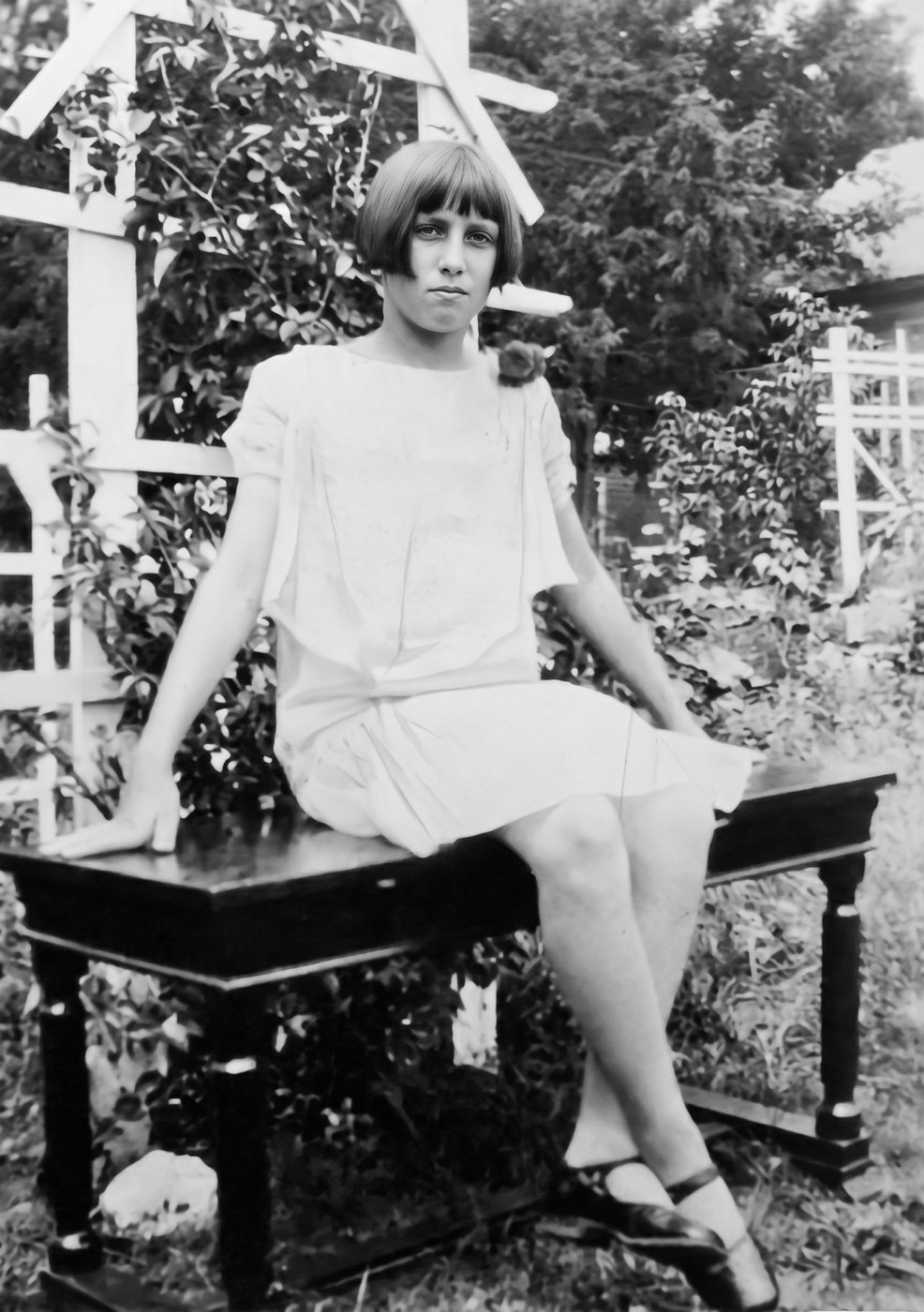 Norma as a girl, sitting on a garden bench