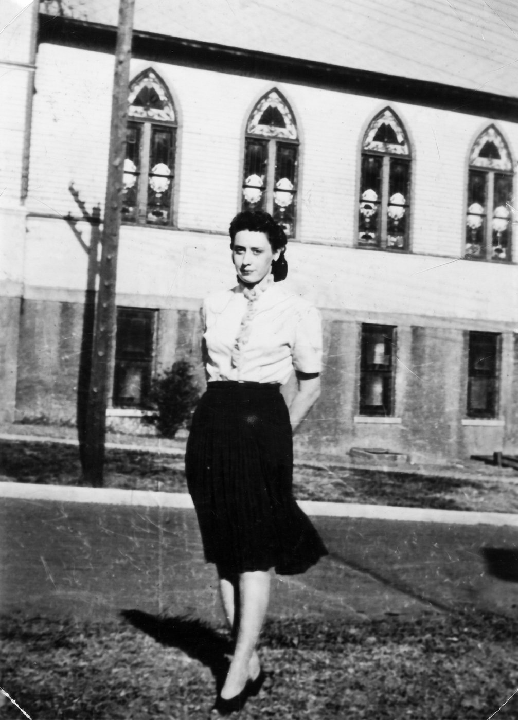 Norma walking on a street in front of a church with arched windows
